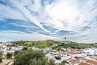 Wide panoramic view of Castro Marim showing traditional white houses with red roofs, streets, and surrounding countryside under a bright sky in the Algarve region of Portugal [IBR124586592]