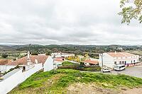 Panoramic view of São Marcos da Serra, a quiet rural village in the Algarve interior of Portugal, featuring traditional white houses, rolling green hills, and a cloudy sky [IBR124586596]