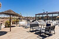 Outdoor terrace with white tables and chairs under thatched umbrellas overlooking riverside landscape near Agua Hotels Riverside in Lagoa, Algarve, Portugal [IBR124586601]
