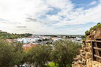 Wide panoramic view of Castro Marim showing traditional white houses with red roofs, streets, and surrounding countryside under a bright sky in the Algarve region of Portugal [IBR124586605]