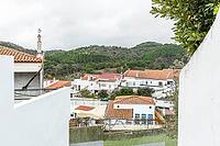 Panoramic view of São Marcos da Serra, a quiet rural village in the Algarve interior of Portugal, featuring traditional white houses, rolling green hills, and a cloudy sky [IBR124586629]