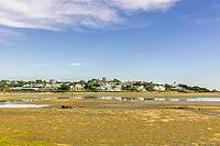 Scenic view of a tranquil coastal lagoon in Quinta do Lago, Algarve, Portugal, featuring shallow waters, natural vegetation, and wading birds under a clear blue sky [IBR124586630]