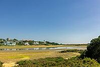 Scenic view of a tranquil coastal lagoon in Quinta do Lago, Algarve, Portugal, featuring shallow waters, natural vegetation, and wading birds under a clear blue sky [IBR124586633]