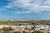Wide panoramic view of Castro Marim showing traditional white houses with red roofs, streets, and surrounding countryside under a bright sky in the Algarve region of Portugal [IBR124586634]
