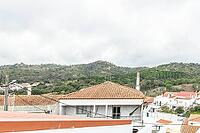 Panoramic view of São Marcos da Serra, a quiet rural village in the Algarve interior of Portugal, featuring traditional white houses, rolling green hills, and a cloudy sky [IBR124586640]