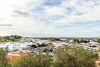 Wide panoramic view of Castro Marim showing traditional white houses with red roofs, streets, and surrounding countryside under a bright sky in the Algarve region of Portugal [IBR124586652]