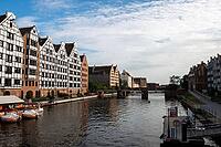 Gdansk, Poland - June 28, 2015 - Historic architecture along riverside with bridges and boats under blue sky [IBR124626845]