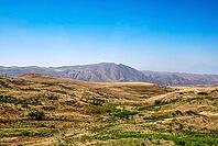 Expansive mountainous landscape with rolling hills under clear blue sky [IBR124626847]