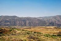 Panoramic view of arid mountain range and grasslands under clear blue sky [IBR124626863]