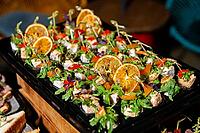 Delightful array of appetizers topped with fresh greens and citrus slices. ideal for summer gatherings or festive occasions, offering vibrant colors and flavors [IBR124626864]