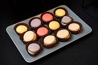 A variety of colorful macarons arranged on a plate. the pastel treats are set against a dark background, showcasing their vibrant hues and delicate textures [IBR124626867]
