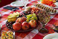 A vibrant assortment of fresh fruits and savory appetizers arranged on a checkered tablecloth. the setting includes apples, grapes, cherries, and an elegant glass, perfect for gatherings [IBR124626890]