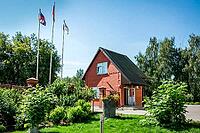 Kolomna, Russia - August 17, 2014 - Charming red brick house with flags in sunny garden setting [IBR124626902]