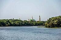 Kolomna, Russia - August 17, 2014 - Serene river with historic russian monastery surrounded by lush forest [IBR124626906]