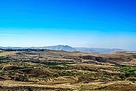 Expansive mountainous landscape with clear blue sky and rolling hills [IBR124626910]