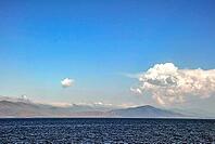 Tranquil mountainous horizon with open sea and expansive cloudy sky [IBR124626912]