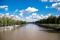 Turku, Finland - August 30, 2014 - Scenic riverbank view with boats and lush greenery under blue sky and clouds [IBR124626917]