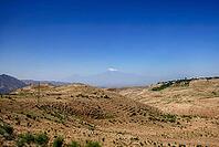 Distant view of snow-capped mountain under clear blue sky across arid landscape [IBR124626923]