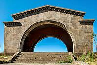 Ancient stone arch with inscriptions under clear blue sky [IBR124626924]