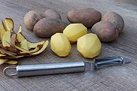 Peeled and unpeeled Laura potatoes with potato peeler, Kempen, North Rhine-Westphalia, Germany [IBR124629544]