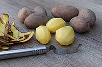 Peeled and unpeeled Laura potatoes with potato peeler, Kempen, North Rhine-Westphalia, Germany [IBR124629548]