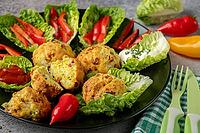 A plate of baked balls, pizza balls surrounded by lettuce leaves, pepper strips and dip [IBR124636272]