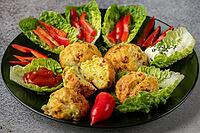 A plate of baked balls, pizza balls surrounded by lettuce leaves, pepper strips and dip [IBR124636275]