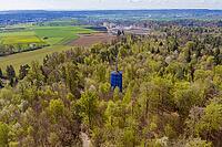 A water tower stands out in the middle of a thick forest full of spring vegetation, Aidlingen, Böblingen district, Germany [IBR124642848]