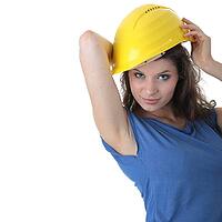 Young female architect or builder wearing a yellow hart hat on a construction site [IBR124692671]