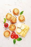 Freshly baked mini pizza on a marble table, with fresh vegetables and cheese, top view [IBR124748950]