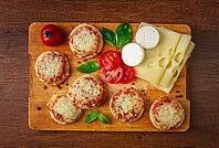 Freshly baked mini pizza, on a wooden board, with fresh vegetables and cheese, top view [IBR124748951]
