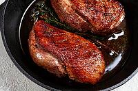 Roast duck breast, in a frying pan, with spices and herbs, close-up, no people [IBR124748956]