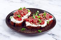 Sandwiches, rye bread with cream cheese, sliced tuna fillet with herbs, breakfast on a black plate, homemade [IBR124748959]