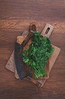 Chopped fresh herbs sit on a wooden cutting board next to a traditional chopping knife. The kitchen atmosphere feels warm and inviting, perfect for cooking enthusiasts [IBR124748962]