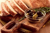 Sliced ciabatta, on a chopping board, with rosemary and olives, Italian bread, close-up, Italian cuisine, breakfast, no people [IBR124748971]