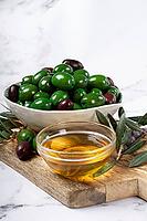 Chalkidiki olives, classic Greek green olives, in a bowl on a cutting board, top view, without people [IBR124748976]