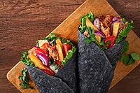 Shawarma in black lavash, on a wooden background, chicken shawarma, no people [IBR124748978]