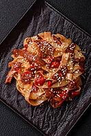 Food, Delicious asian udon dish with vegetables, meat, salt and spices on a ceramic plate on a dark concrete background [IBR124773705]