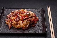 Food, Delicious asian udon dish with vegetables, meat, salt and spices on a ceramic plate on a dark concrete background [IBR124773707]
