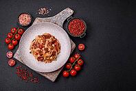 Food, Delicious asian udon dish with vegetables, meat, salt and spices on a ceramic plate on a dark concrete background [IBR124773708]
