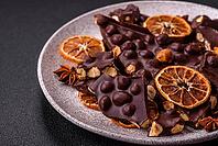 Food, Black bitter chocolate with whole hazelnuts, candied fruits and mint, broken into pieces on a dark concrete background [IBR124773715]