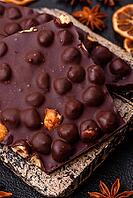 Food, Black bitter chocolate with whole hazelnuts, candied fruits and mint, broken into pieces on a dark concrete background [IBR124773717]
