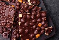 Food, Black bitter chocolate with whole hazelnuts, candied fruits and mint, broken into pieces on a dark concrete background [IBR124773719]