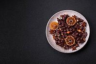 Food, Black bitter chocolate with whole hazelnuts, candied fruits and mint, broken into pieces on a dark concrete background [IBR124773725]