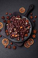 Food, Black bitter chocolate with whole hazelnuts, candied fruits and mint, broken into pieces on a dark concrete background [IBR124773727]