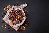 Food, Black bitter chocolate with whole hazelnuts, candied fruits and mint, broken into pieces on a dark concrete background [IBR124773729]