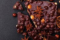 Food, Black bitter chocolate with whole hazelnuts, candied fruits and mint, broken into pieces on a dark concrete background [IBR124773734]
