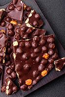 Food, Black bitter chocolate with whole hazelnuts, candied fruits and mint, broken into pieces on a dark concrete background [IBR124773735]