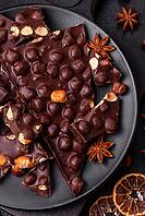 Food, Black bitter chocolate with whole hazelnuts, candied fruits and mint, broken into pieces on a dark concrete background [IBR124773740]