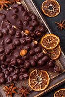 Food, Black bitter chocolate with whole hazelnuts, candied fruits and mint, broken into pieces on a dark concrete background [IBR124773745]